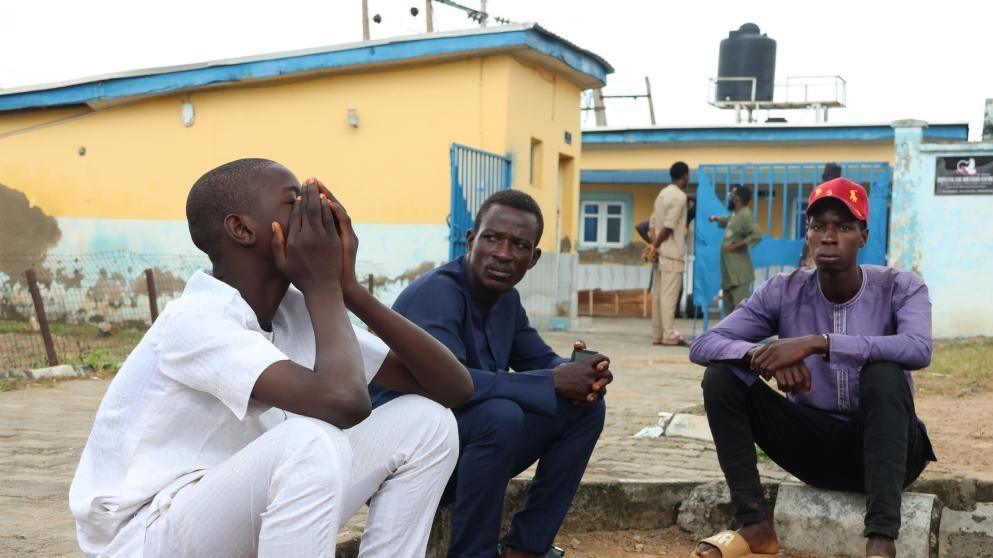 Family members sit outside the General Hospital to reclaim the bodies of their relatives