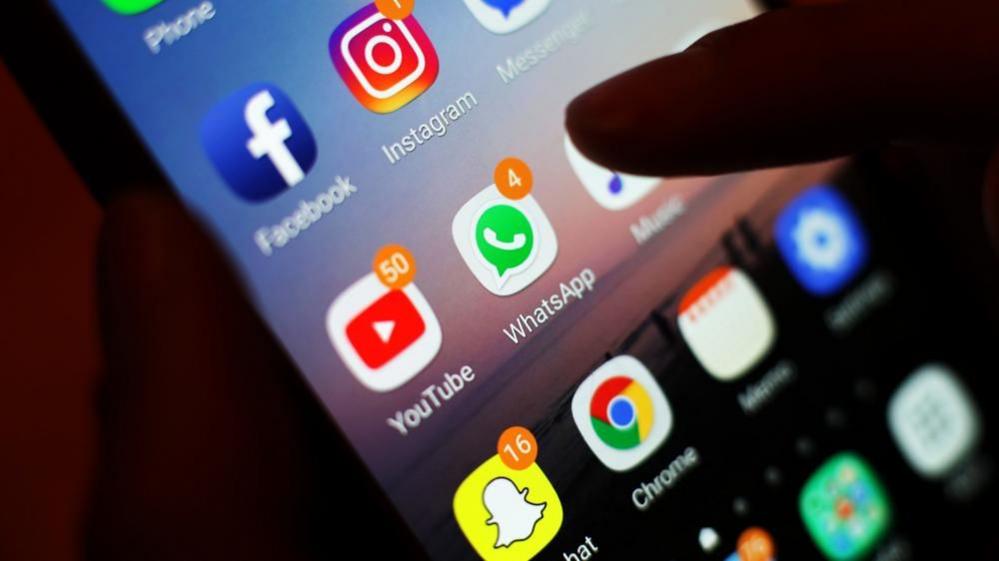 Icons of social media apps including Facebook, Instagram, YouTube and WhatsApp on a mobile phone screen