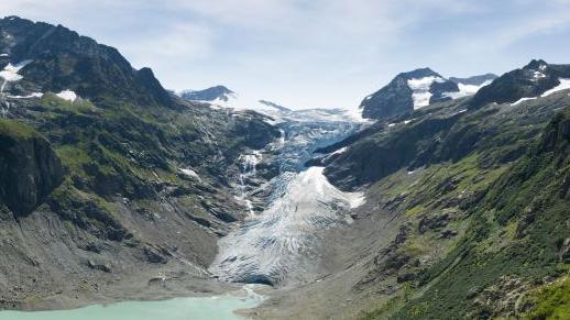 A blue lagoon underneath a white snowy glacier
